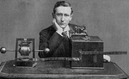 Black and white photo of Guglielmo Marconi with one of his first models of radio.