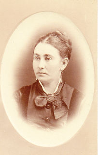 Sepia portrait of Zoé Lafontaine in her youth. Her hair is pulled back in a bun and she is wearing pendant ear rings,a scarf knotted in a bow and a cameo. She is facing left and looking to the photographer's left.