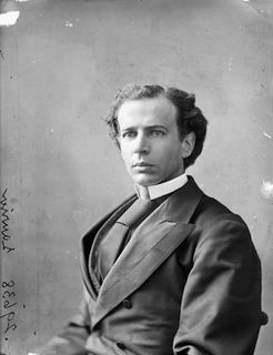Black and white photo of Laurier seated on a chair and dressed in a suit and neck tie that seem too big for him. He is looking at and facing the photographer's right.