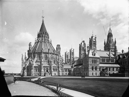 Vue du parlement d'Ottawa et de sa grande bibliothèque de forme circulaire à toi en pointe. On retrouve sur la pointe du toi une croix.